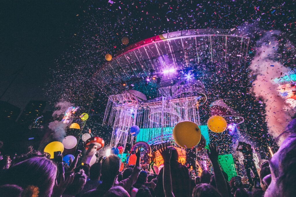 Exciting night concert with confetti, balloons, and a lively audience enjoying the vibrant atmosphere.